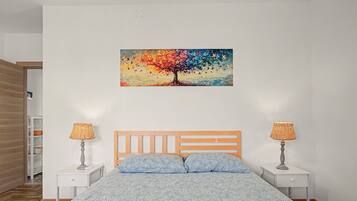 Un dormitorio con una cama, dos mesitas de noche, un cuadro en la pared y un armario de madera.