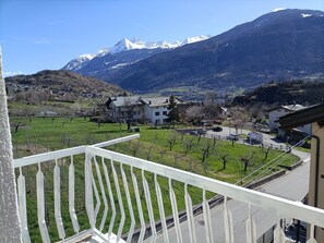 A balcony with a view of a mountainous landscape, a village, and a road with vehicles. - Apartment 'Vista Sulla Grivola' with Mountain View, Private Garden and Wi-Fi (Saint-Pierre)