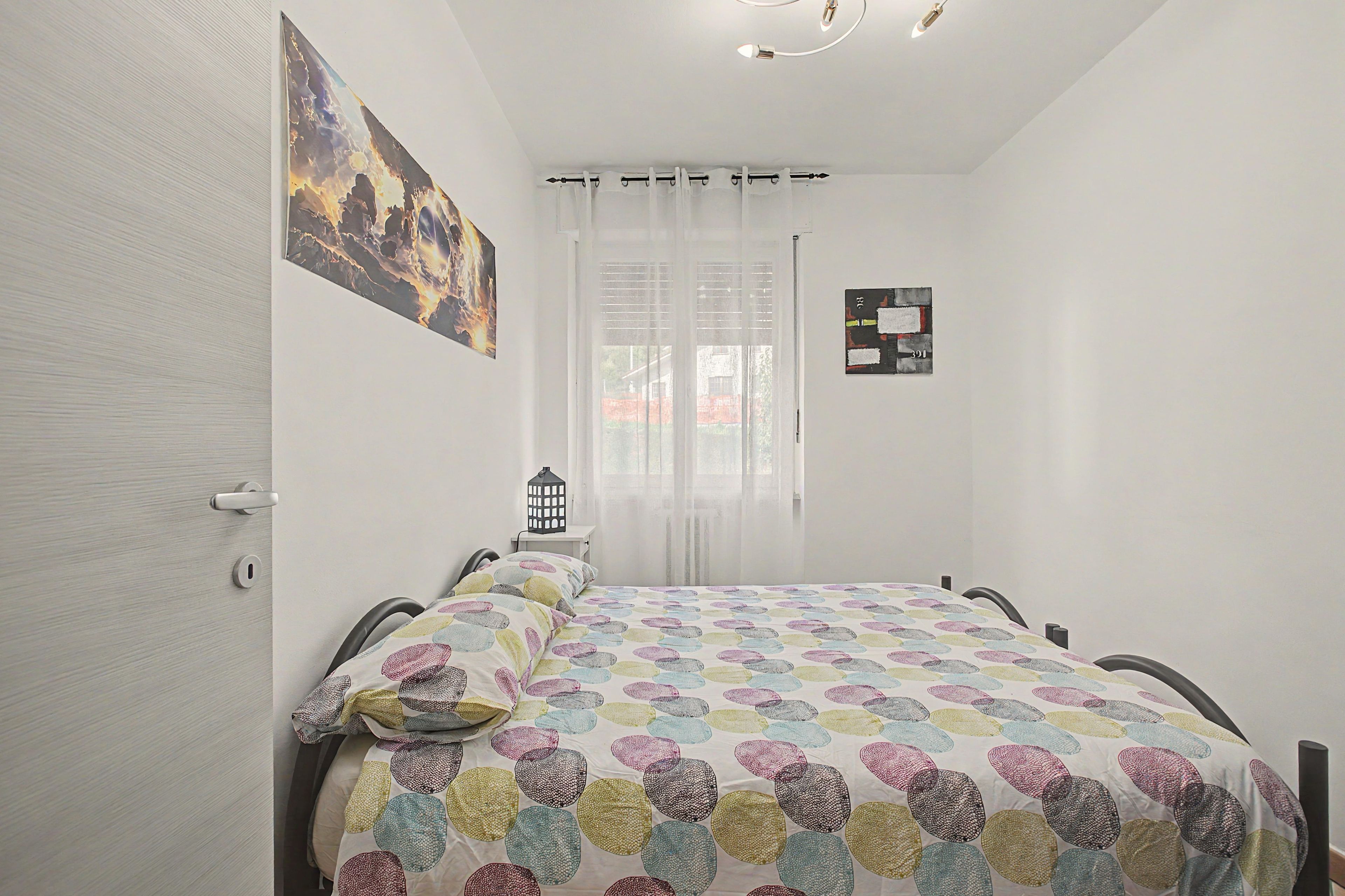 Une chambre à coucher avec un lit, une table de chevet, une lampe et un tableau accroché au mur.
