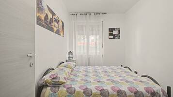 Une chambre à coucher avec un lit, une table de chevet, une lampe et un tableau accroché au mur.