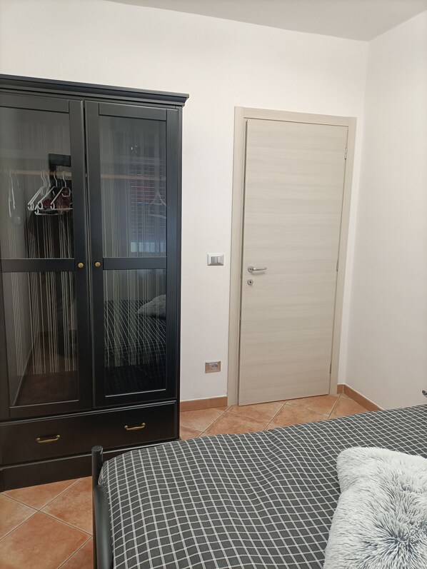 Un dormitori amb un llit, un armari i una porta.