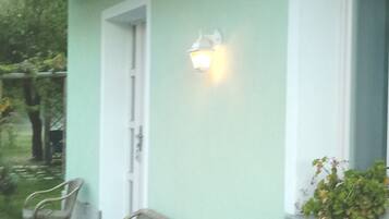 A house with a porch, a door, and a wall-mounted light fixture.