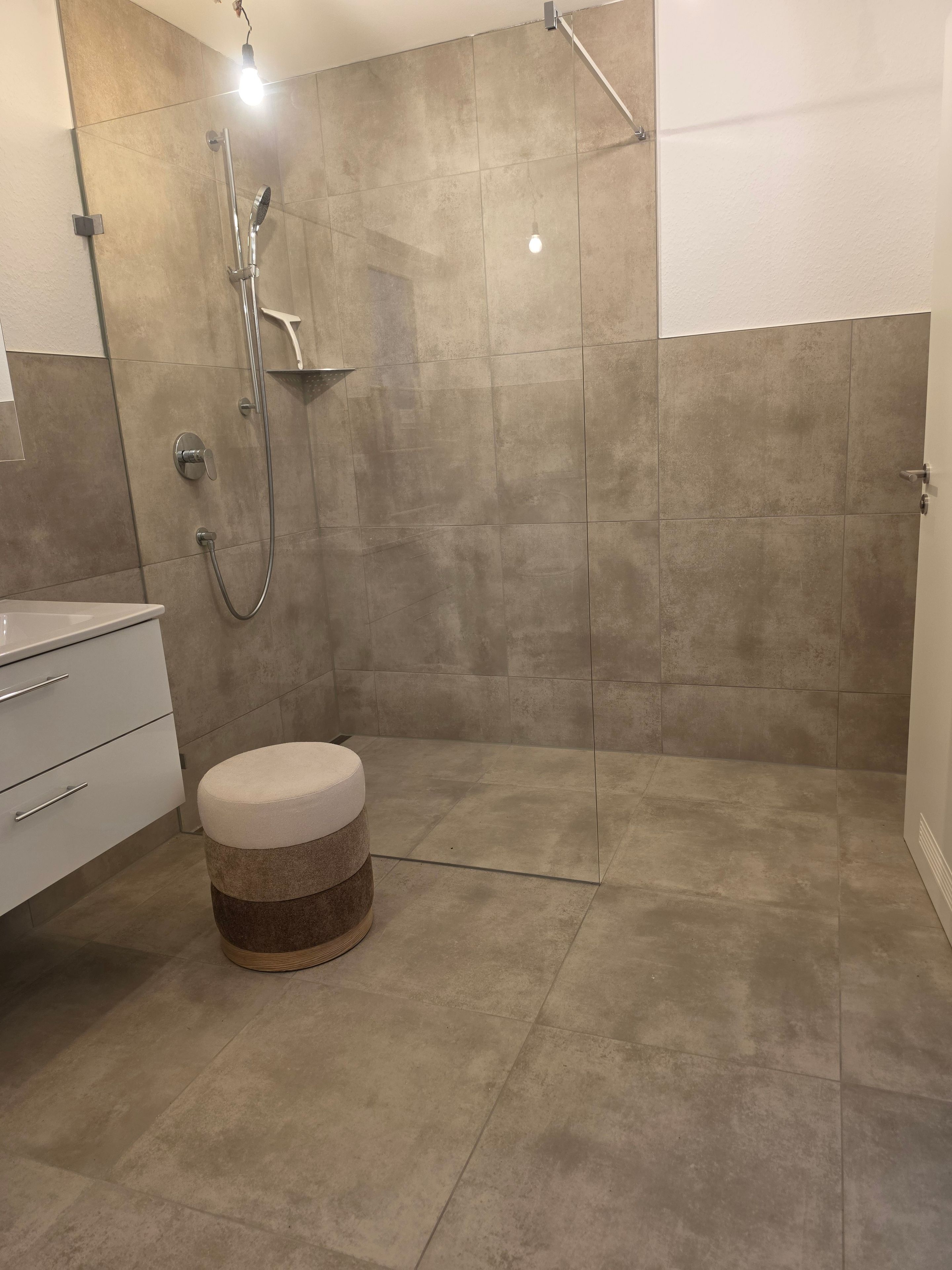 A bathroom with a shower, a toilet, and a vanity with drawers.