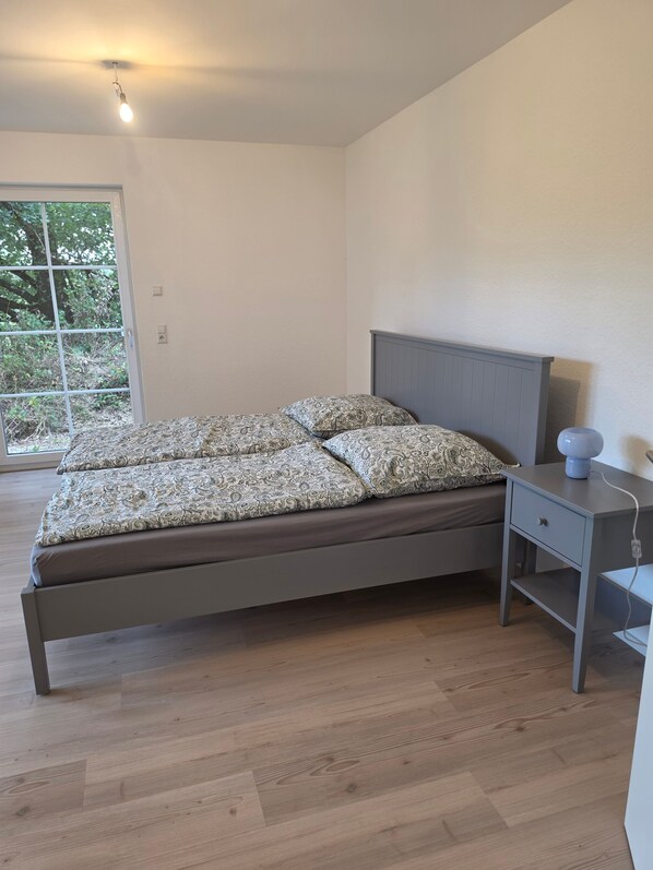 Quarto com cama, mesa de cabeceira e janela.