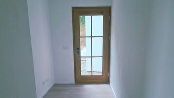 A narrow hallway with wooden flooring and white walls.