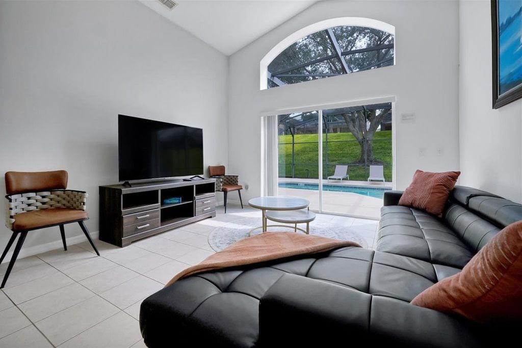 Relax in this bright living room with comfortable seating, a large TV, and direct access to your private pool.S