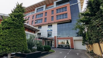 A modern hotel building with a glass facade, a visible entrance, and a sign indicating it is a Days Hotel.