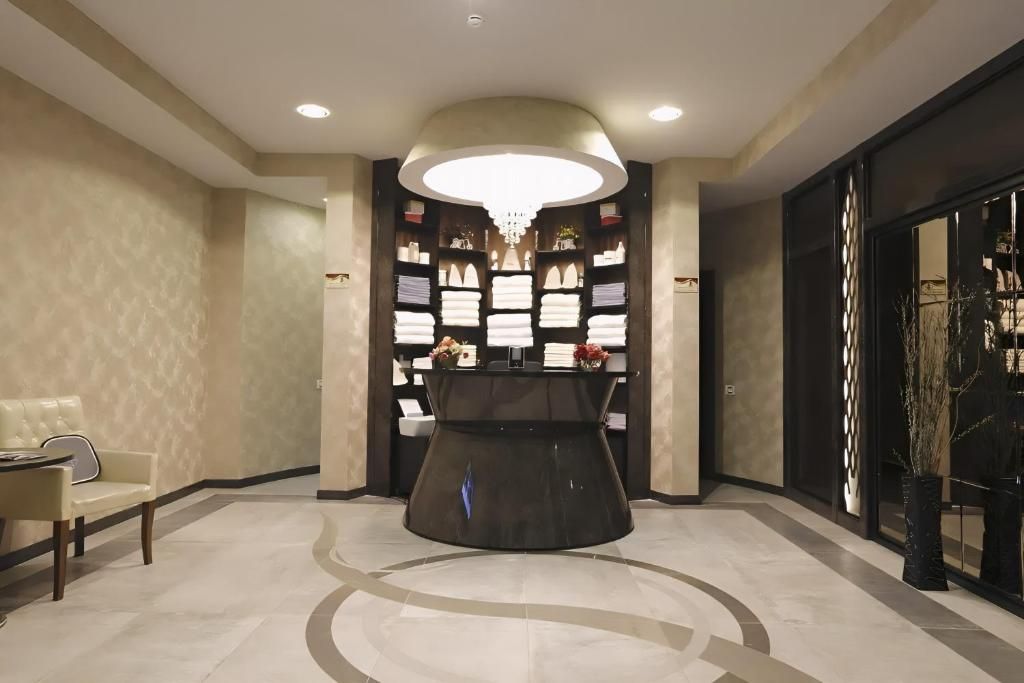A reception area with a central desk, a seating area with a chair, and a decorative wall with framed items.