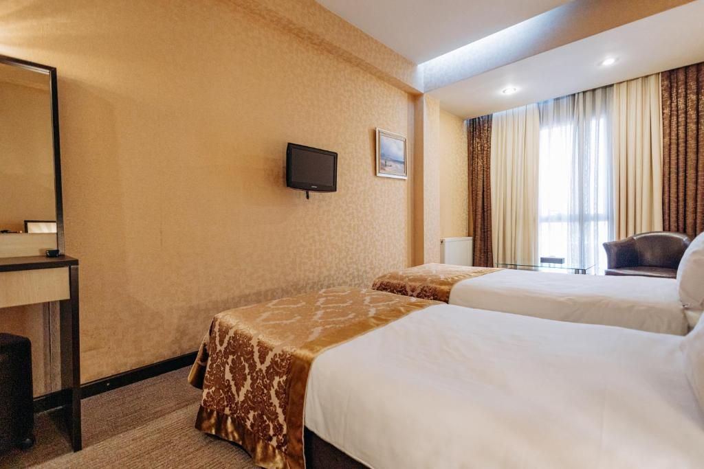 Una habitación de hotel con dos camas, televisión, escritorio y una silla.