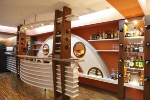 A bar area with a curved counter, shelves with bottles, and a mirror. - DaysHotelBaku (Baku)