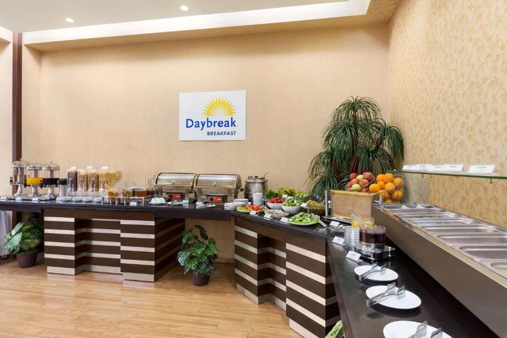 A buffet area with a sign for 'Daybreak Breakfast,' featuring a variety of food items and a plant.
