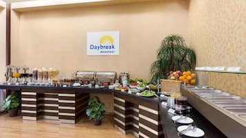 Een buffetgedeelte met een bordje 'Daybreak Breakfast', met diverse soorten eten en een plant.