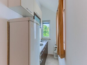A compact kitchen with a refrigerator, a window, and a sink. - 1 Bedroom Apartment With Terrace (Postira)