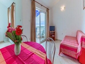 A room with a table, chairs, a bed, a TV, and a view of the sea through a glass door. - 1 Bedroom Apartment With Terrace (Postira)