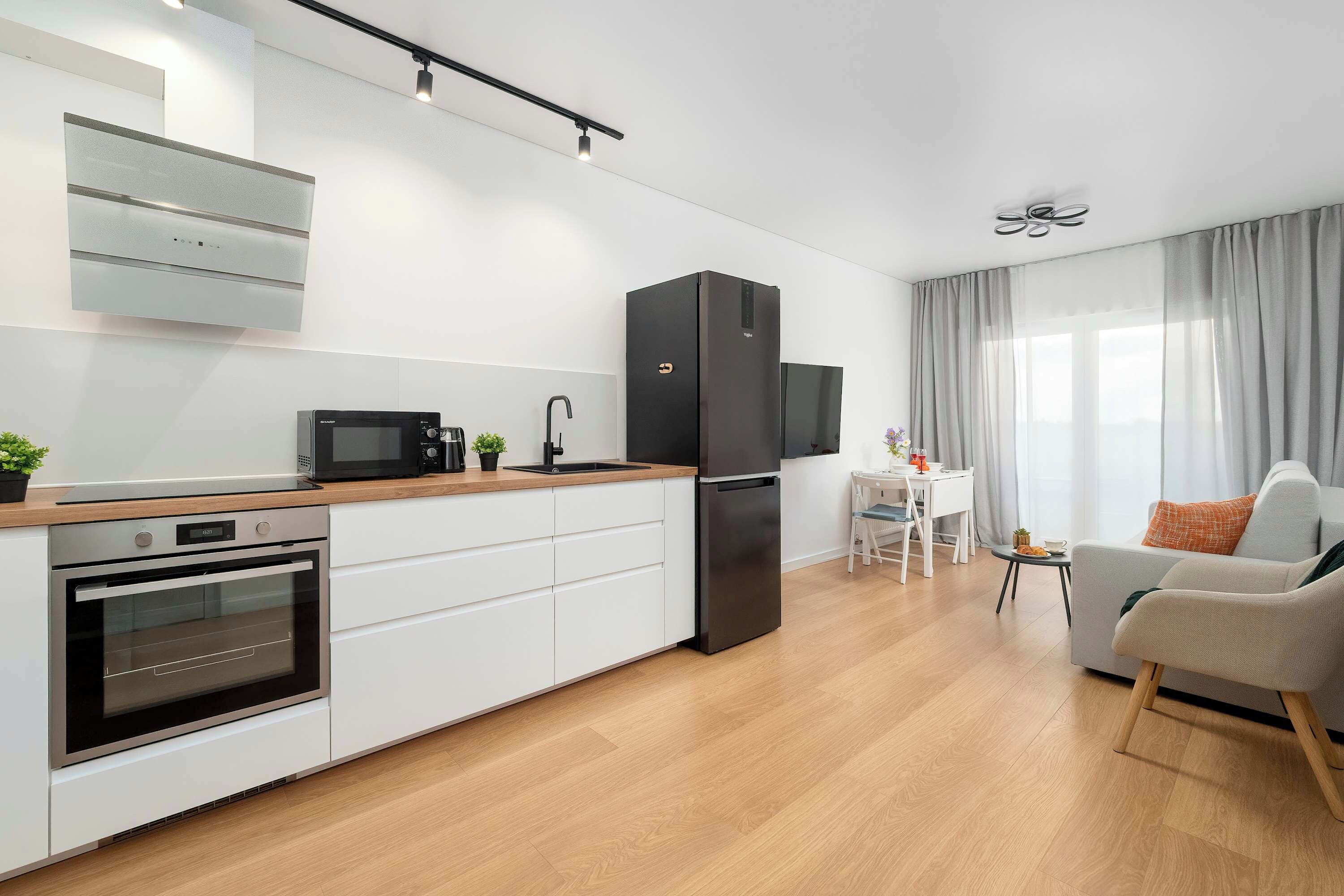 Een moderne keuken met een inbouwoven, magnetron en een zwarte koelkast.
