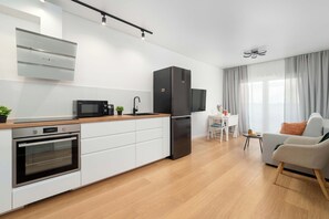 Een moderne keuken met een inbouwoven, magnetron en een zwarte koelkast.
