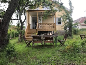 A wooden deck with a table and chairs, surrounded by greenery. - 8 Person Holiday Home in Bovallstrand (Bovallstrand)