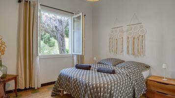 A bedroom with a bed, a window with curtains, a bedside table, and a wall decoration.