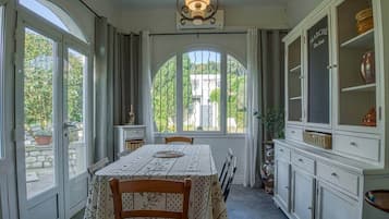 Ein Esszimmer mit Tisch, Stühlen, einem Schrank mit Glastüren und Blick aus dem Fenster.