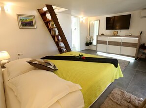 Ein Schlafzimmer mit einem Bett, einem Nachttisch, einer Lampe und einem Fernseher an der Wand.