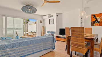 A modern living room with a sofa, dining table, chairs, and a TV.