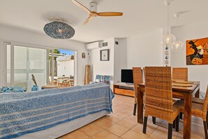 Una sala de estar moderna con sofá, mesa de comedor, sillas y televisor.