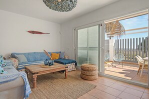 A living room with a sofa, coffee table, and a view through a sliding glass door to an outdoor patio.