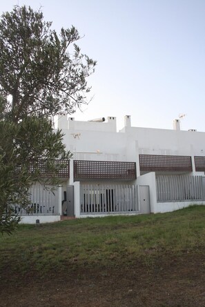 Een modern gebouw met een plat dak, witte gevels en een metalen hek.