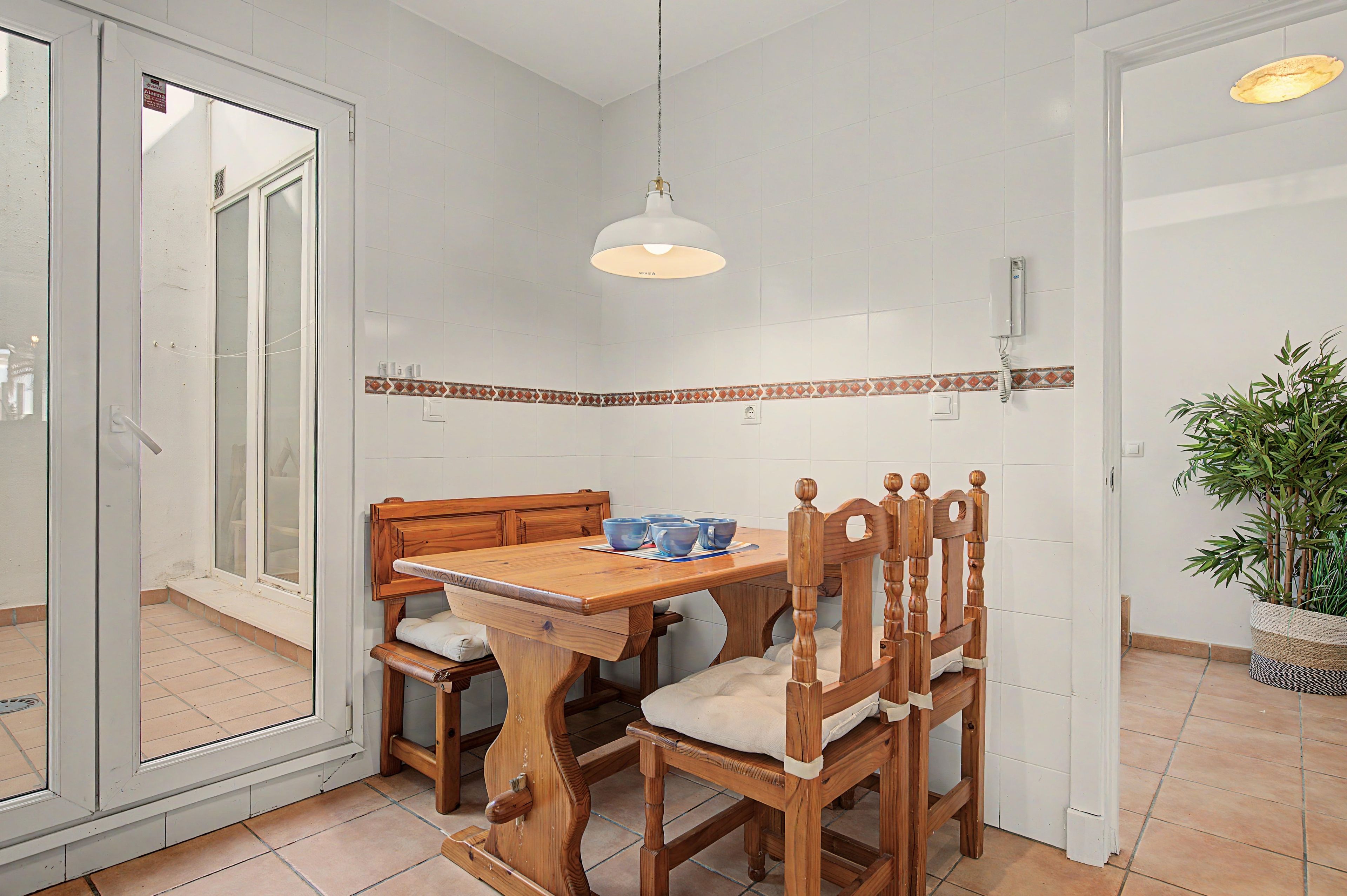 Un coin repas avec une table et des chaises en bois, un luminaire suspendu et une plante en pot.