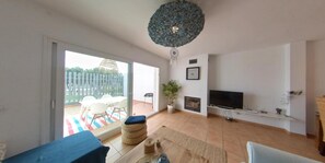 A living room with a TV, a fireplace, and a balcony with outdoor furniture.