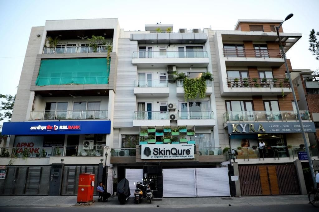 Een meerhoog gebouw met commerciële bedrijven op de begane grond, waaronder een bank, een huidverzorgingskliniek en een kapsalon.
