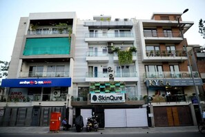 Um edifício de vários andares com estabelecimentos comerciais no térreo, incluindo um banco, clínica de cuidados com a pele e um salão de beleza.