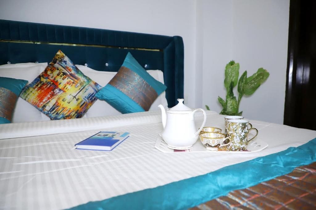 A neatly made bed with a white bedspread, a blue headboard, and a decorative pillow.