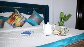A neatly made bed with a white bedspread, a blue headboard, and a decorative pillow.