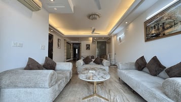 A modern living room with two sofas, a marble coffee table, recessed ceiling lights, and a ceiling fan.