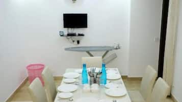 Un coin repas avec une table dressée pour quatre personnes, un ventilateur de plafond, un téléviseur fixé au mur et un luminaire fixé au mur.