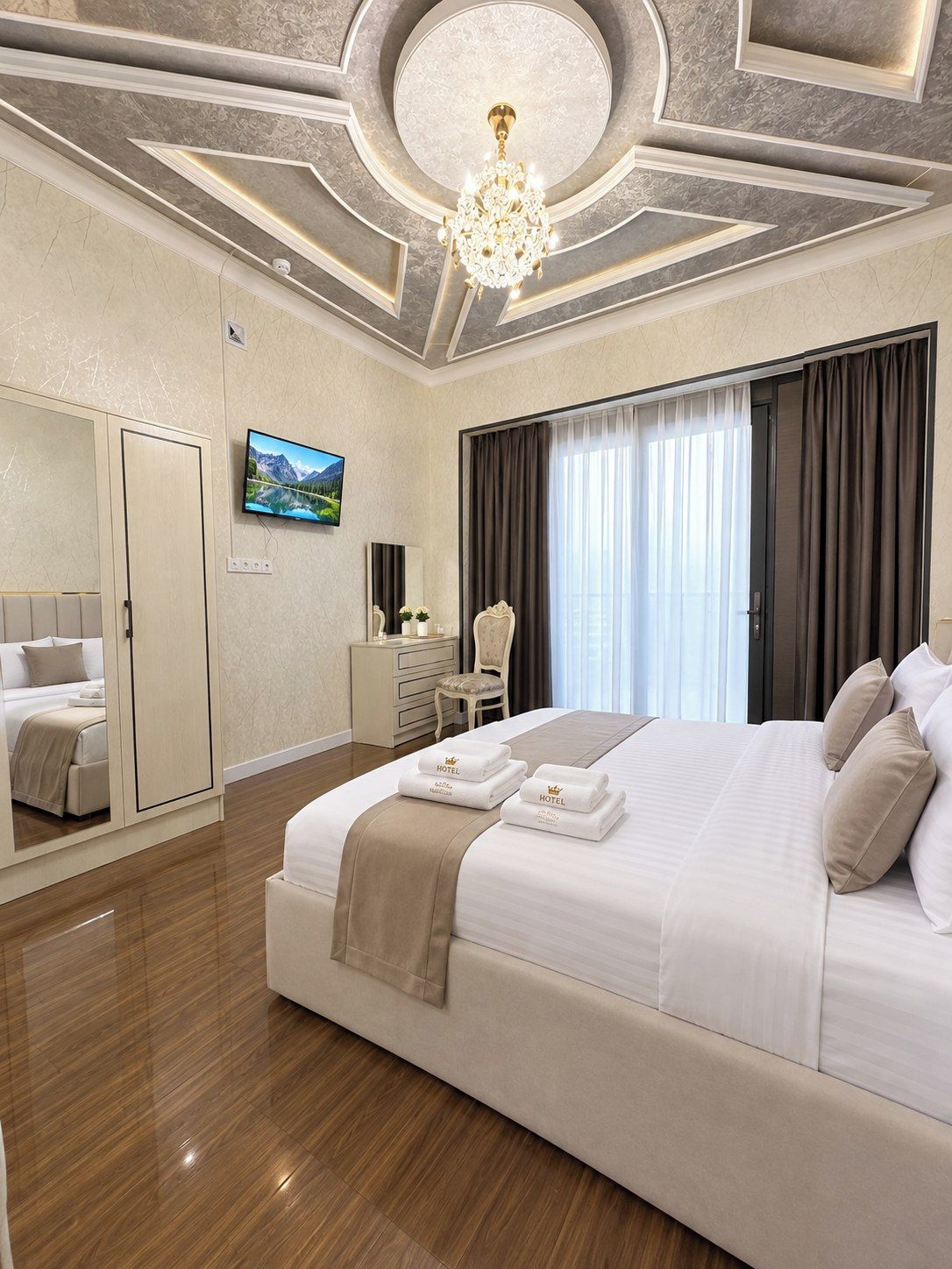 Ein Hotelzimmer mit einem großen Bett, einem Fernseher, einem Kleiderschrank, einem Schreibtisch und einer Kandelaber.