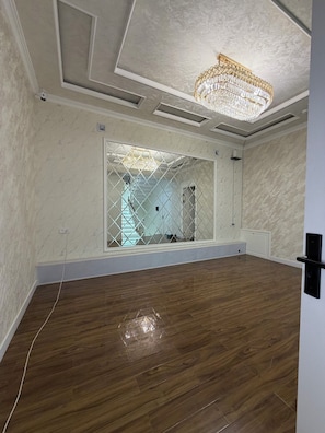 A room with a wooden floor, a chandelier, and a large window with a geometric pattern. - Happy Stay (Tashkent)