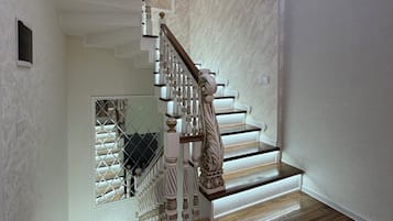 Una escalera con barandillas decorativas y una baranda de madera, que conduce a un rellano con una puerta de cristal.