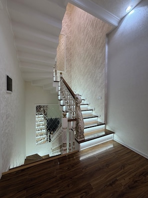 A staircase with ornate balusters and a wooden handrail, leading to a landing with a glass door. - Happy Stay (Tashkent)
