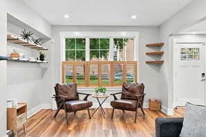 Une pièce comprenant deux fauteuils en cuir, une petite table avec une plante et une grande fenêtre à carreaux.