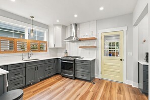 A modern kitchen with grey cabinets, a stainless steel range hood, and a wooden floor. - NEW! Royal Dragonfly - Sleeps 10 - Downtown Wilm. (Wilmington)