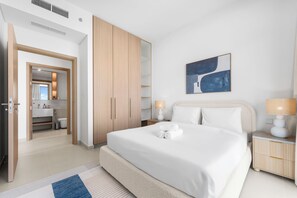 Ett hotellrum med en säng, ett badrum, en garderob och en tavla på väggen.
