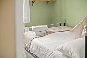A neatly made bed with a white comforter and pillows, a rolled white towel on the bed, and a wooden headboard. - Town centre l 1bd apt l 5 min to station (Hertfordshire)