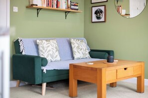Um quarto com um sofá verde, uma mesa de centro de madeira e uma estante com livros.