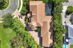 Ett flygbildsfoto av en bostadsfastighet med ett stort hus, en swimmingpool och en välskött trädgård.