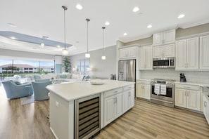 A modern kitchen with white cabinetry, stainless steel appliances, and a large island. - Esplanade Golf & Country Club (Naples)