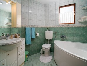 A bathroom with a sink, toilet, and bathtub, tiled in a light color, with a window above the toilet. - Apartments Tomas - One Bedroom Apartment With Balcony (Omis)