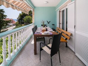 A balcony with a table set for dining, chairs, a bench, and a view of the street. - Apartments Tomas - One Bedroom Apartment With Balcony (Omis)