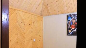A room with a bed, wooden walls, a small window, and a painting.
